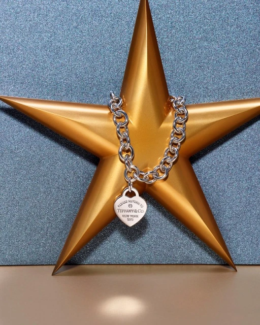 Silver Tiffany & Co heart pendant necklace on a gold star against a textured blue background in a close-up studio shot.