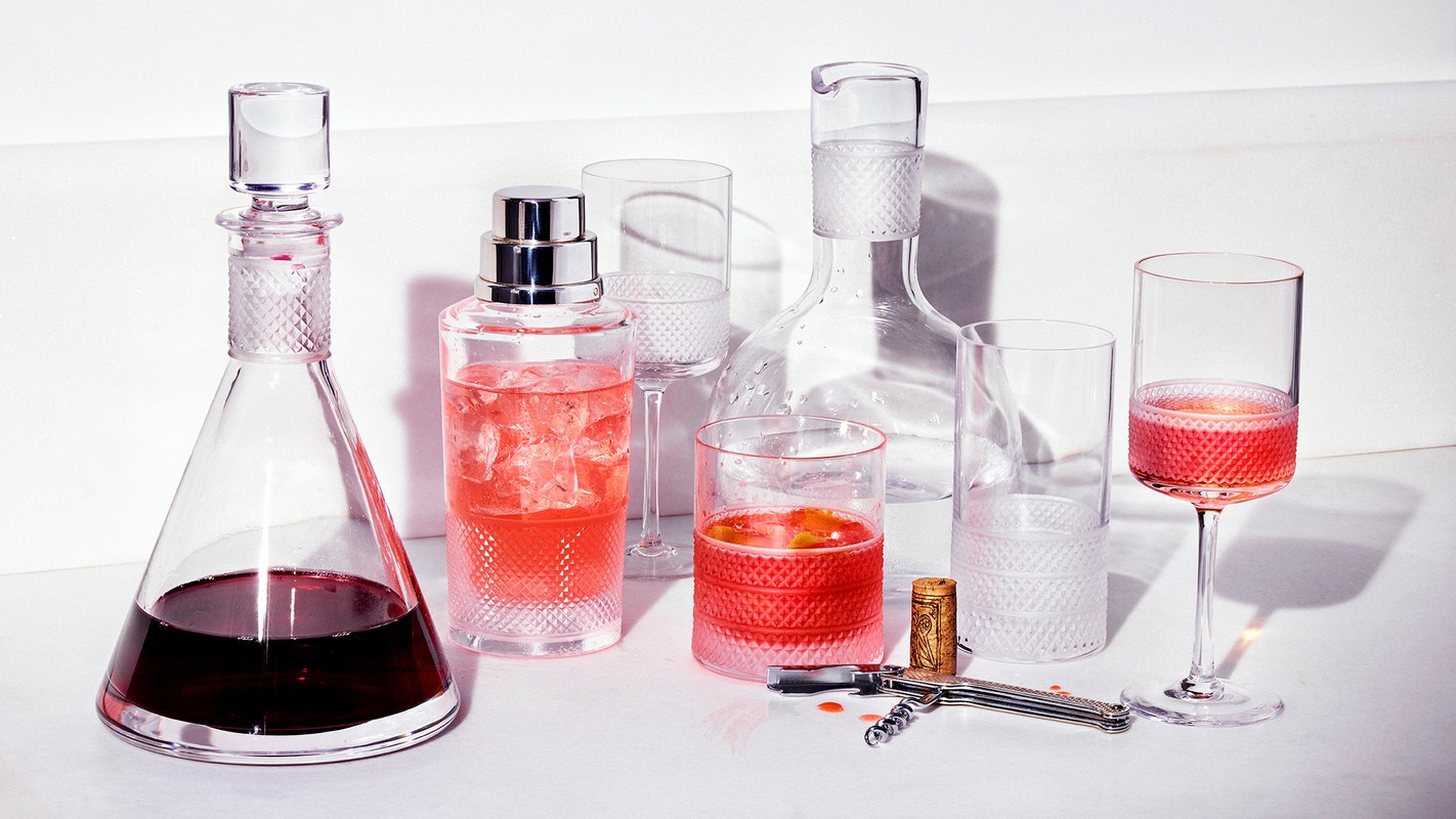 Elegant glassware with colorful cocktails and wine, arranged on a white surface with a wine opener, creating a vibrant and sophisticated visual.