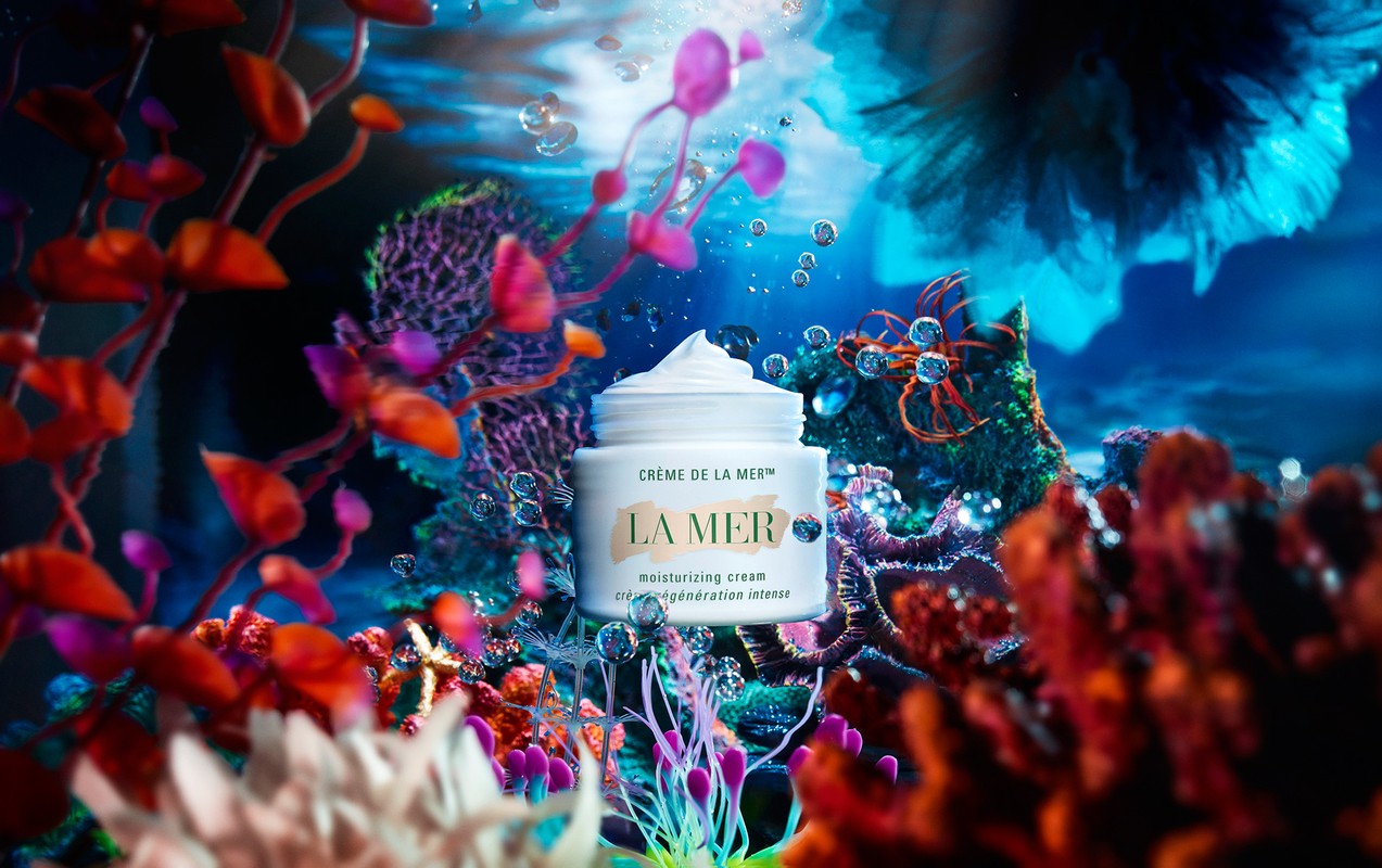 La Mer moisturizing cream jar amidst vibrant coral reef, water bubbles. Beauty product in underwater setting, marine-themed, luxury skincare.