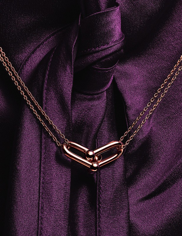 Close-up of a gold chain link necklace with a purple silk background. Jewellery advertisement, fashion accessory photography.