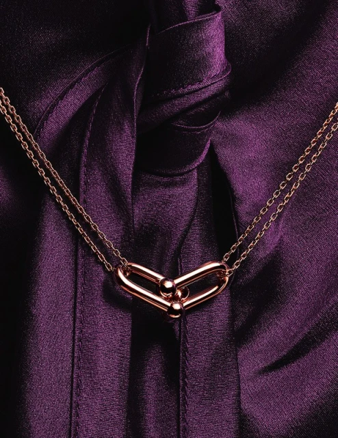 Close-up of a gold chain link necklace with a purple silk background. Jewellery advertisement, fashion accessory photography.