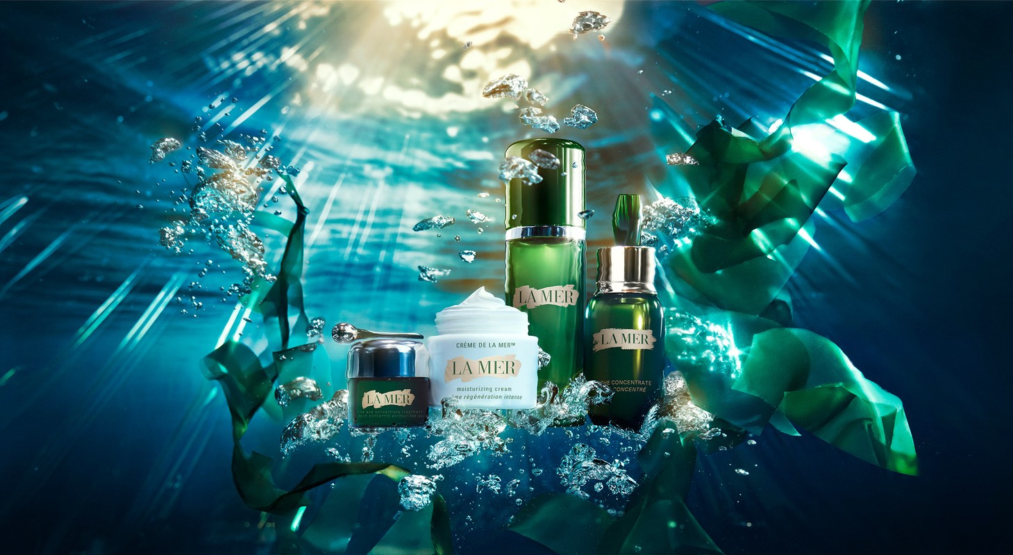 La Mer skincare product line featuring moisturizing cream, concentrate, and lotion in an underwater-themed shot with bubbles and blue lighting.