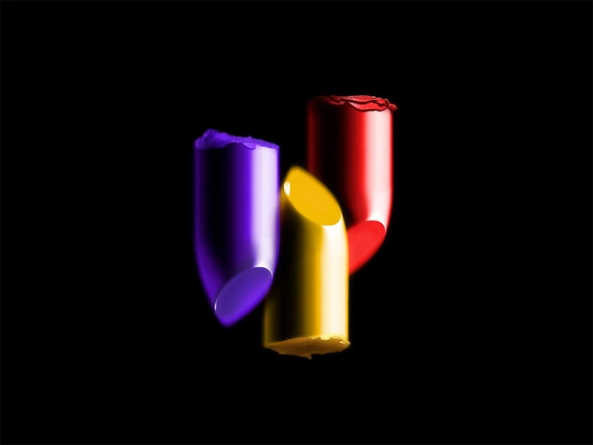 Three lipsticks in red, purple, and yellow arranged on a black backdrop, perfect for beauty and cosmetic advertising or artistic representation.