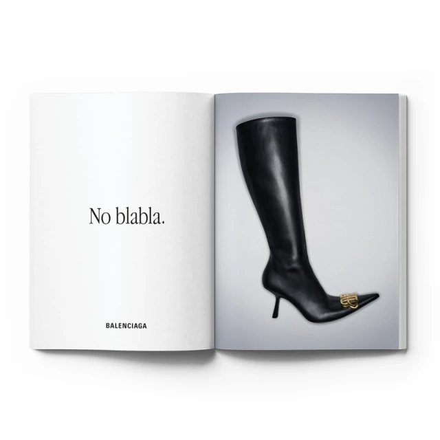 Fashion editorial shot of black Balenciaga stiletto boot on white studio background with a spread from a luxury fashion magazine.