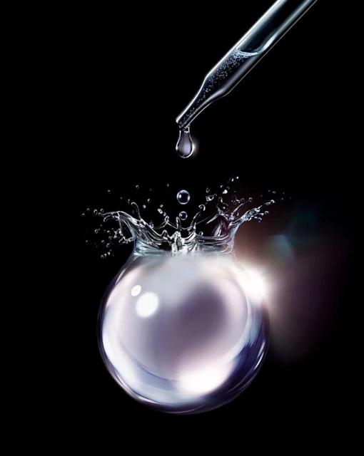 Dropper dispensing liquid into orb causing a splash against black background. Liquid textures create a clean, bright, and modern aesthetic.