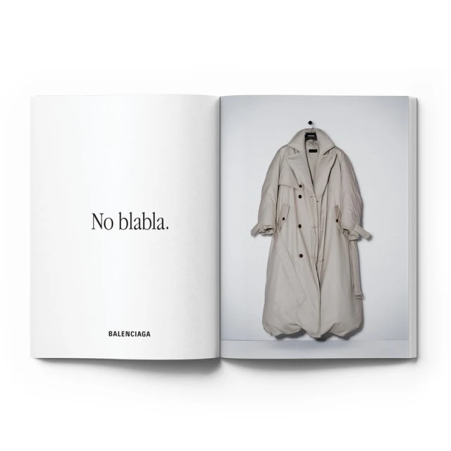 Fashion editorial featuring a Balenciaga trench coat hanging on a white wall, photographed in an open book with accompanying text.