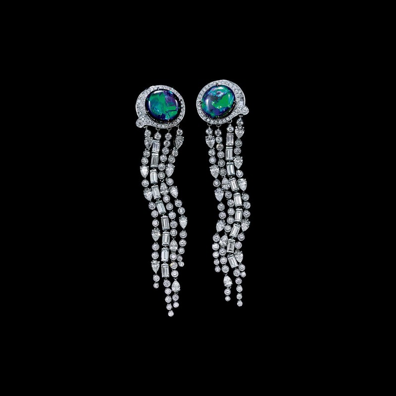 Elegant dangle earrings featuring large, round, iridescent gems surrounded by diamonds on a black background, jewelry close-up.