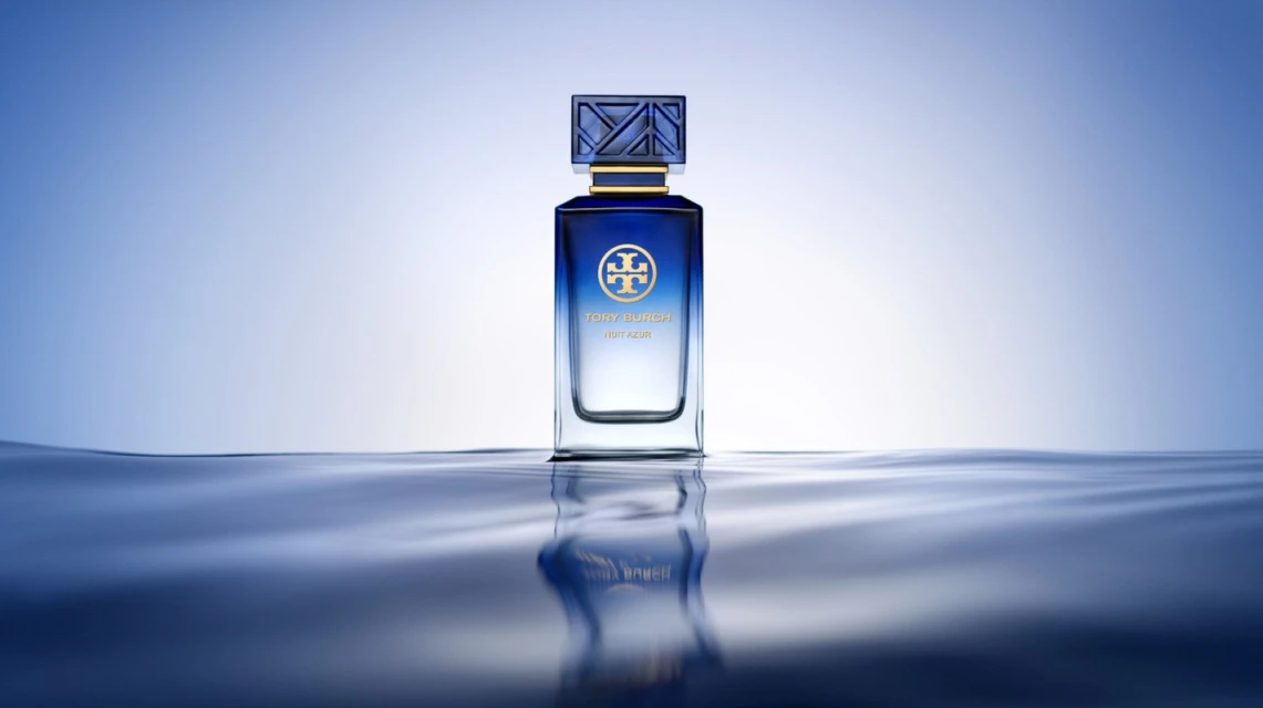 Tory Burch 'Fleur Azur' perfume bottle on a reflective water surface, blue color scheme, clean studio product shot, and beauty aesthetic.