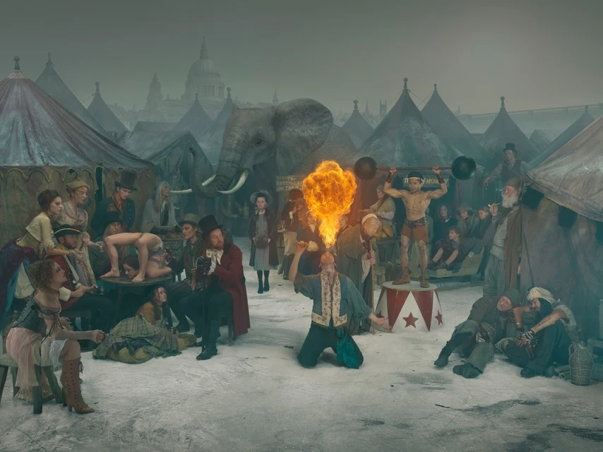 Intricate scene featuring a crowd of circus performers and spectators with an elephant, tents, and a city skyline in the background.