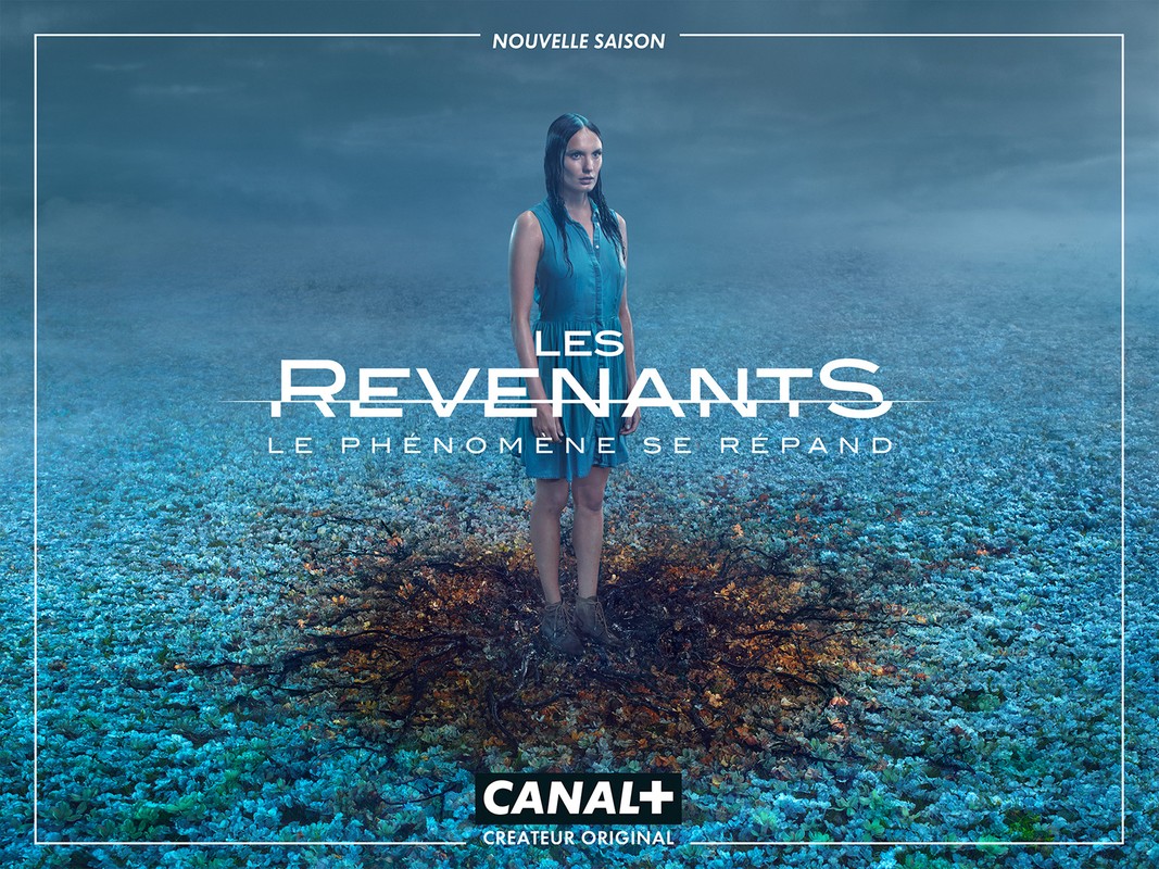 A young woman stands ankle-deep in dark liquid in a mysterious, otherworldly scene with a blue, cloudy sky. TV show poster.