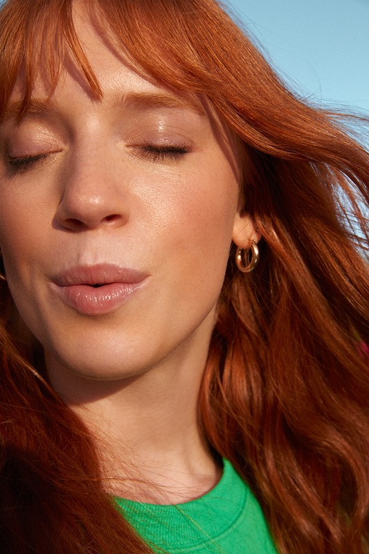 Close-up portrait of a woman with long red hair and closed eyes wearing a bright green top by photographer Kat Borchart.