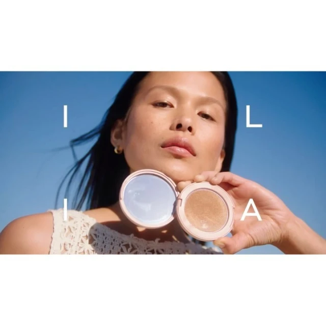 Asian woman presents a round compact mirror and a bronzer compact outdoors with blue sky. Make-up, beauty, and cosmetics product shot.
