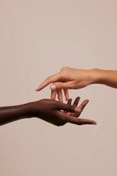 Two hands with different skin tones gently touching against a neutral light grey seamless background