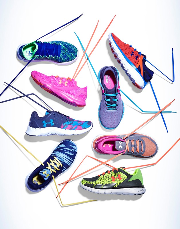 Collection of Under Armour athletic shoes in various colors, arranged on a white surface with linear design elements.