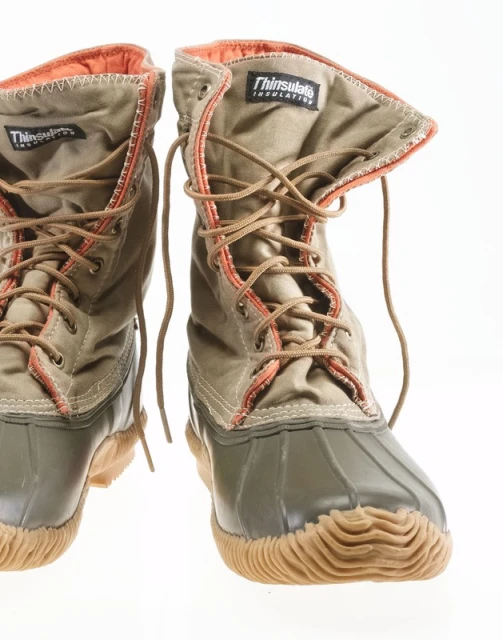 Pair of tan and olive green duck boots with brown laces on a white backdrop, showcasing outdoor footwear with durable construction.