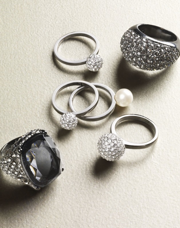 Collection of silver rings with crystal and pearl accents on a light surface, showcasing elegant and modern jewelry design.