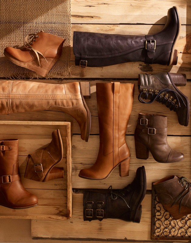 Collection of women's leather boots in various styles arranged on a wooden surface with natural light highlighting textures and details.