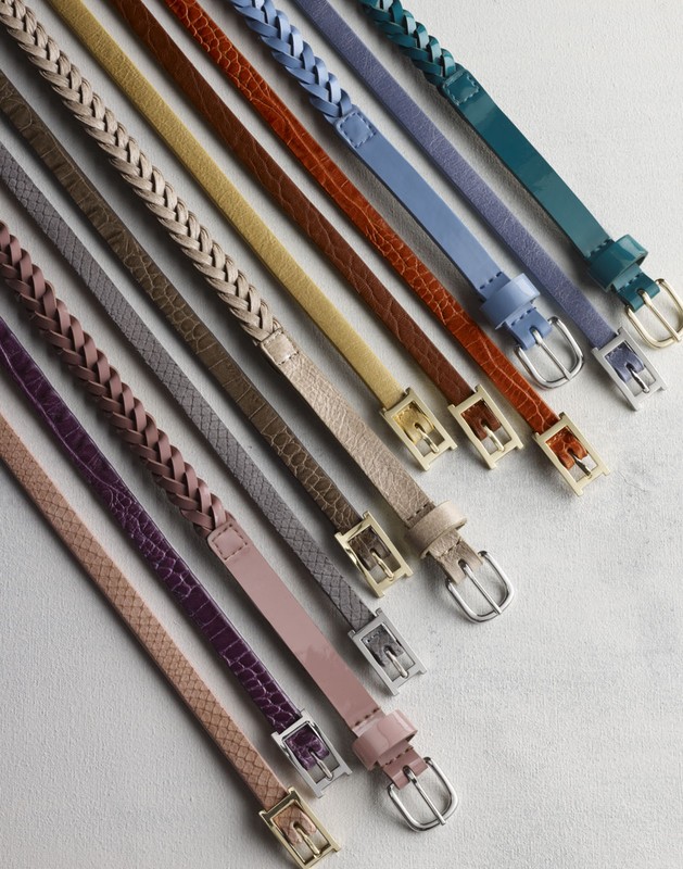 Array of colorful thin belts with various textures and braided designs, all arranged on a flat surface with silver or gold buckles.