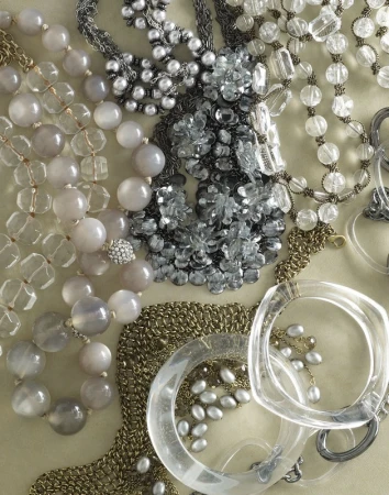 Assorted necklaces and bracelets of various materials, including beads, crystals, and clear bangles, displayed on a neutral surface.