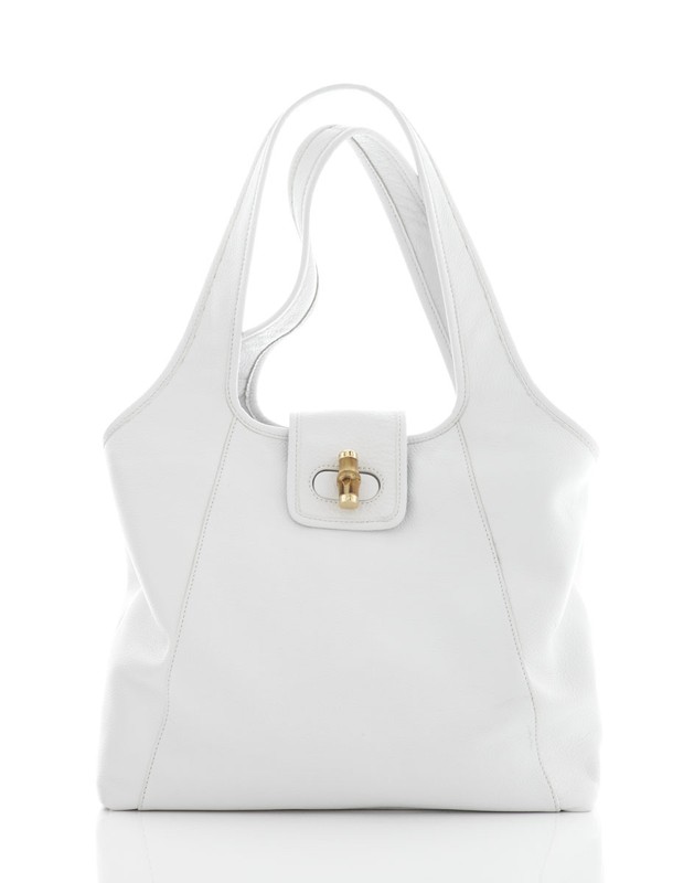 Elegant white leather tote bag with gold clasp on a reflective white surface, showcasing its texture and simple design.