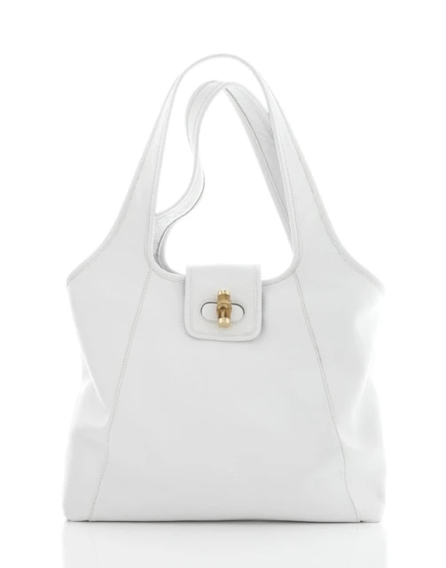 Elegant white leather tote bag with gold clasp on a reflective white surface, showcasing its texture and simple design.