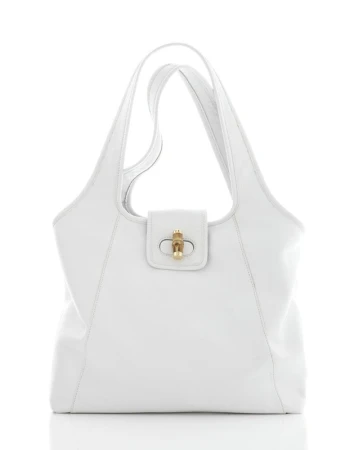 Elegant white leather tote bag with gold clasp on a reflective white surface, showcasing its texture and simple design.
