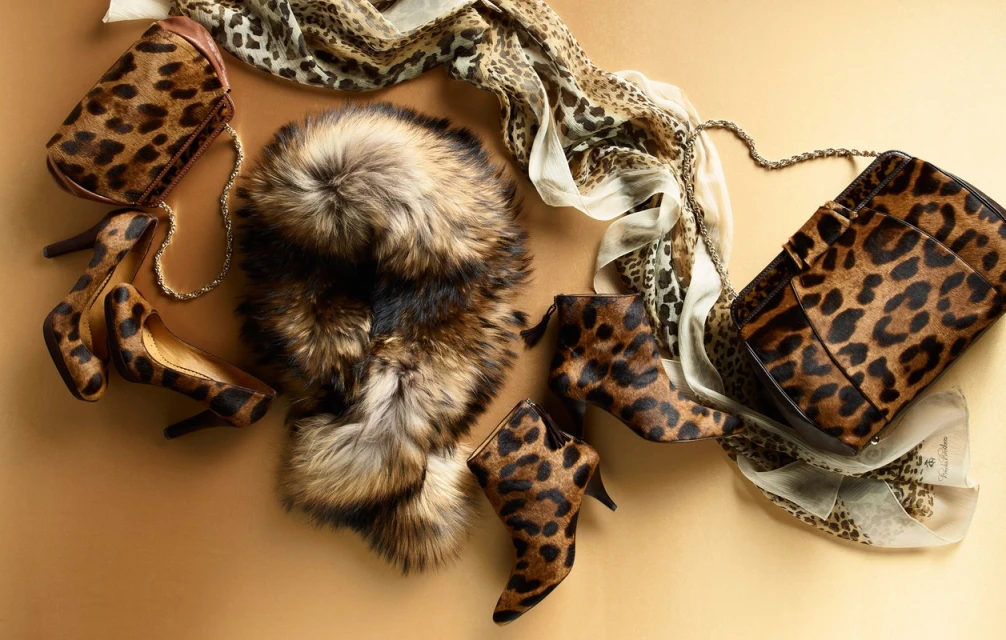 Fashion layout featuring a leopard print handbag, heels, booties, and a scarf, plus a fur collar against a neutral background.