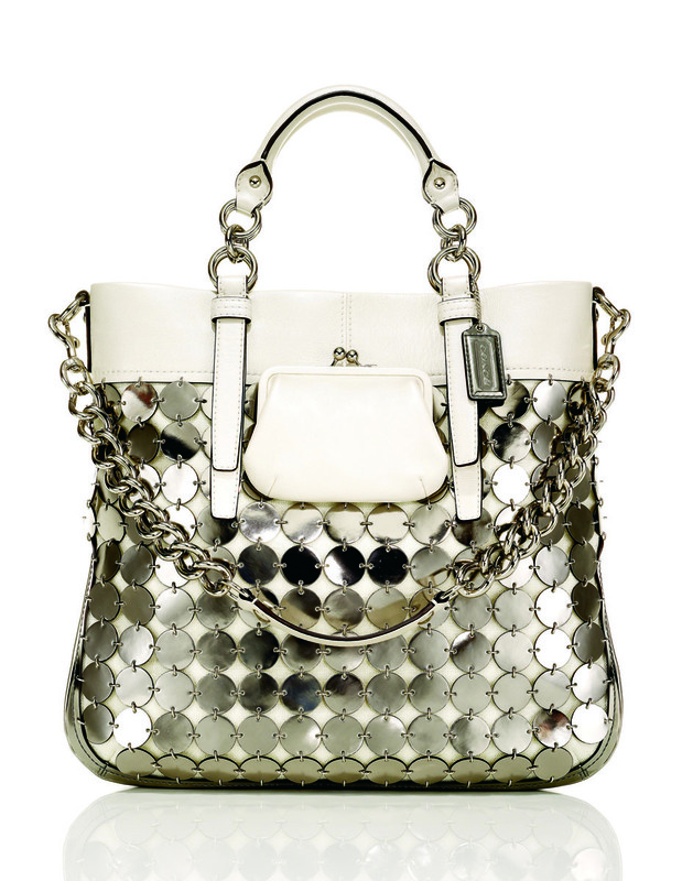 White Coach purse with silver circular sequin detail and silver chain. Fashion accessory with top handles on a white background.