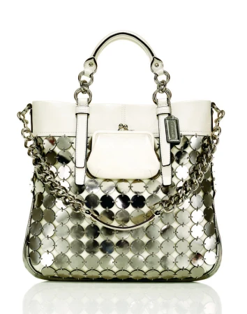 White Coach purse with silver circular sequin detail and silver chain. Fashion accessory with top handles on a white background.