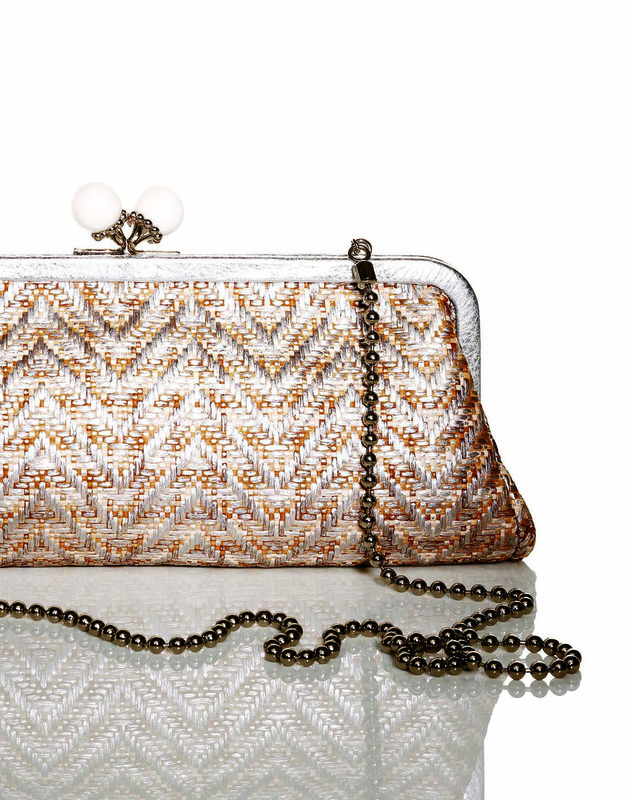 Elegant woven clutch handbag with beaded handle on a reflective white surface, studio shot, stylish fashion accessory.