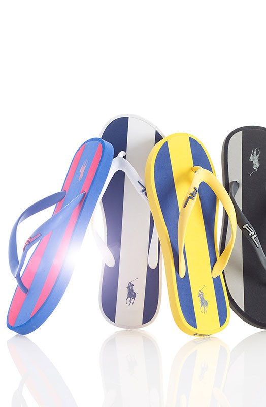 Four pairs of Ralph Lauren striped flip-flops in blue, yellow, white, and black. Summer footwear featuring the RL polo logo.