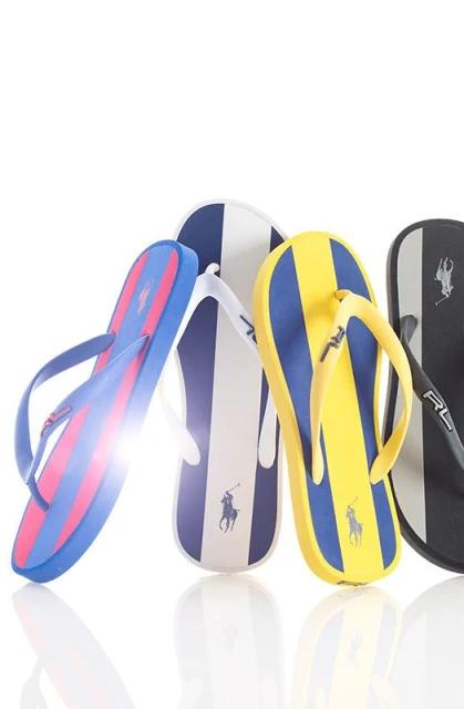 Four pairs of Ralph Lauren striped flip-flops in blue, yellow, white, and black. Summer footwear featuring the RL polo logo.