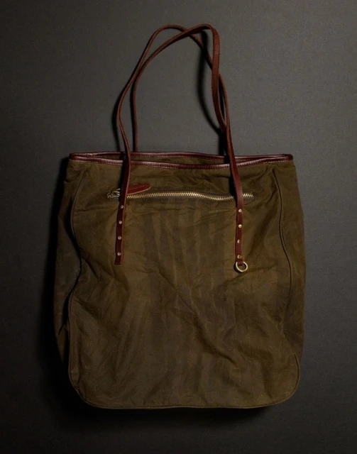Olive green tote bag with brown leather straps on a dark grey background, showcasing fashion accessory and design.