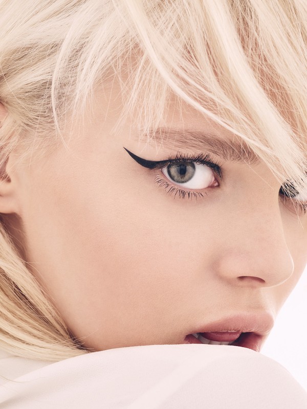 Close-up of a young adult woman with light blonde hair and dramatic black winged eyeliner. Beauty shot for beauty or fashion concept.