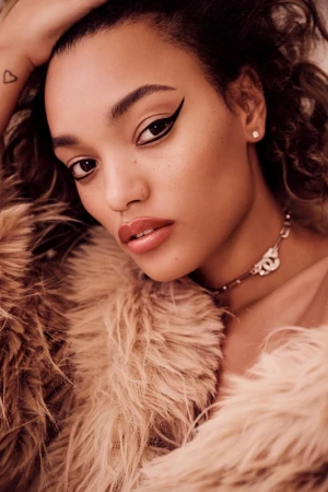Close-up portrait of a young woman wearing winged eyeliner and a fluffy faux fur coat, photographed by Kate Powers.