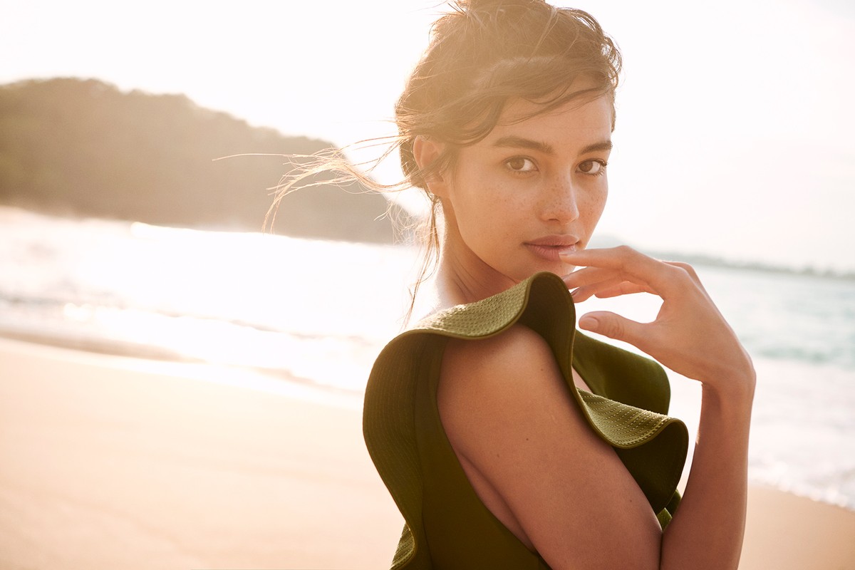 Woman in an olive green ruffled top on a sandy beach at sunset, photographed by Kate Powers.