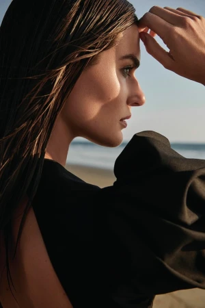 Profile portrait of a woman with wet hair wearing a black top outdoors by the beach, photographed by Kate Powers.