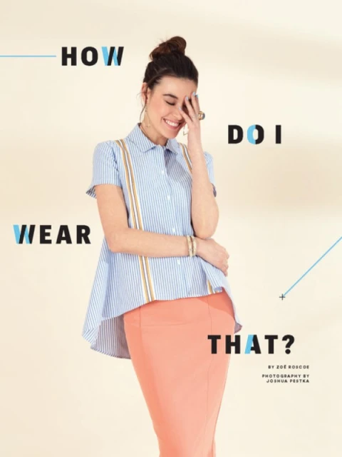 A stylish woman with a topknot poses in a striped shirt and coral skirt against a light backdrop, showcasing a fashion editorial look.