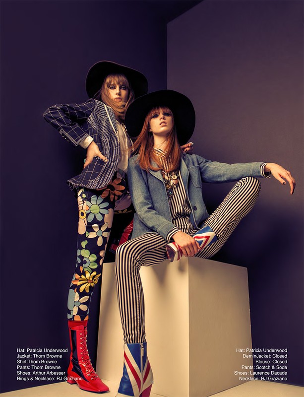 Two fashion models in patterned blazers and pants pose in a studio against a grey wall. The image emphasizes vibrant textile designs.