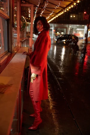 Woman in red coat and red boots standing on a wet city street at night with hair styled by Katsumi Matsuo