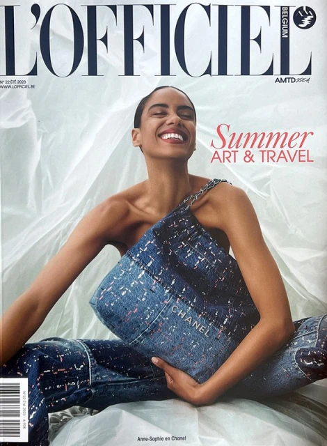 L'Officiel Belgium cover featuring a smiling woman holding a Chanel handbag, wearing matching denim pants, in a photo studio setting.