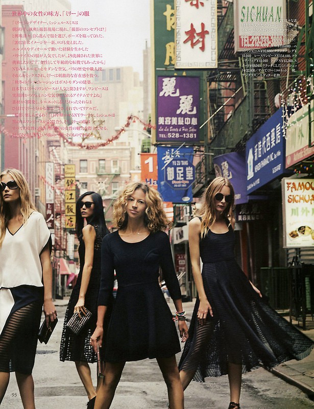 Fashion editorial shot outdoors on a city street featuring five female models in dresses, sunglasses, and stylish poses against a backdrop of Asian signage.