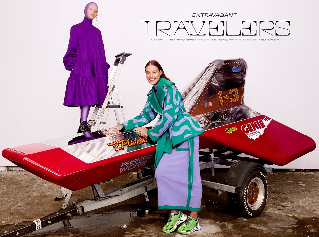 Two fashion models pose with an airplane-like vehicle wearing retro-inspired purple and green outfits in a studio setting.