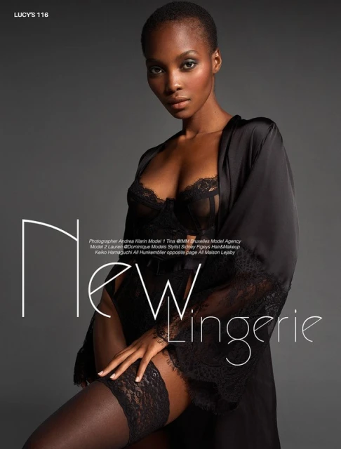 Elegant portrait of a Black woman in black lingerie and robe, seated against a gray background, showcasing fashion and beauty.