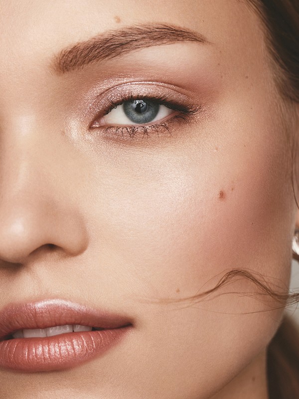 Close-up portrait of a woman's face highlighting natural makeup, glossy nude lips, and soft shimmering eyeshadow by Keiko Takagi.