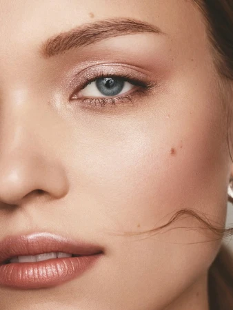 Close-up portrait of a woman's face highlighting natural makeup, glossy nude lips, and soft shimmering eyeshadow by Keiko Takagi.