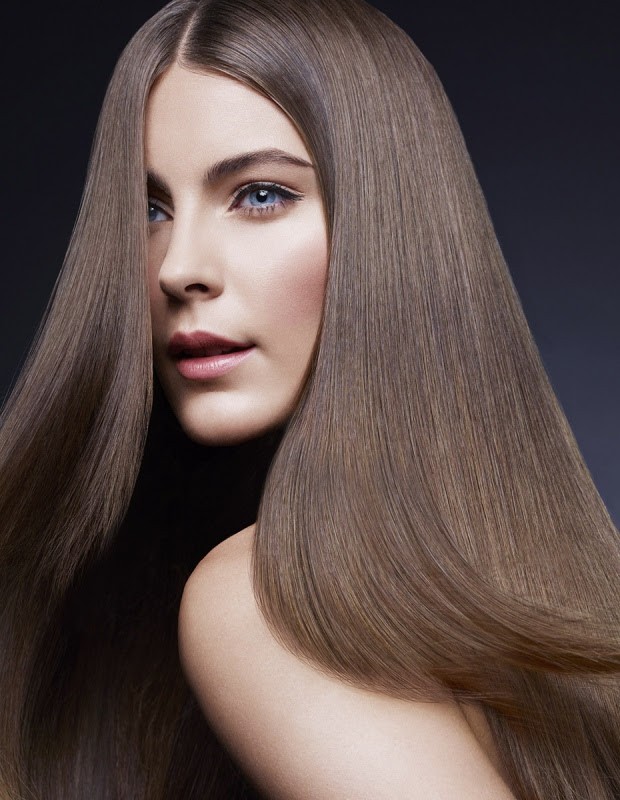 Portrait of a beautiful woman with long straight brown hair, fair skin, blue eyes. Fashion and beauty shot with a dark gray background.