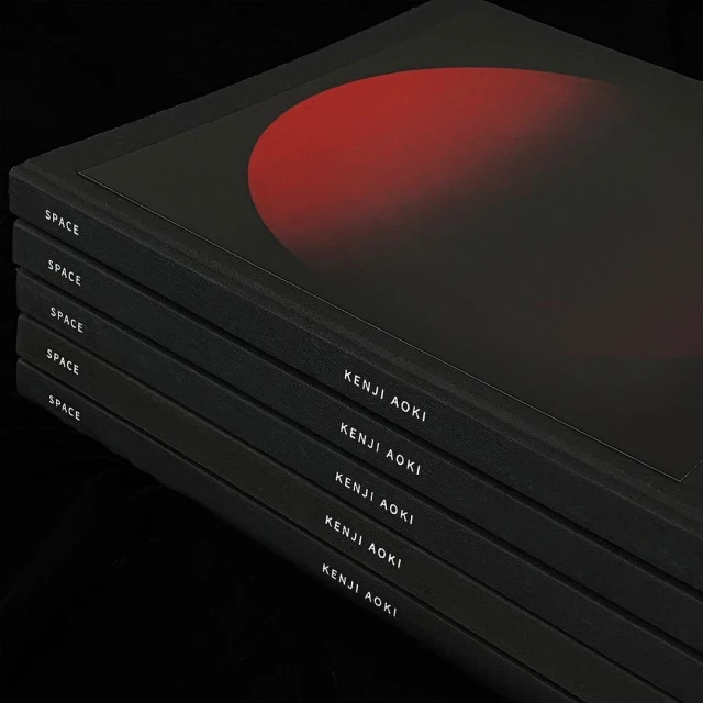 Stack of five black books with red planet design and the text 'Space' and 'Kenji Aoki' visible on the spines on a black surface.