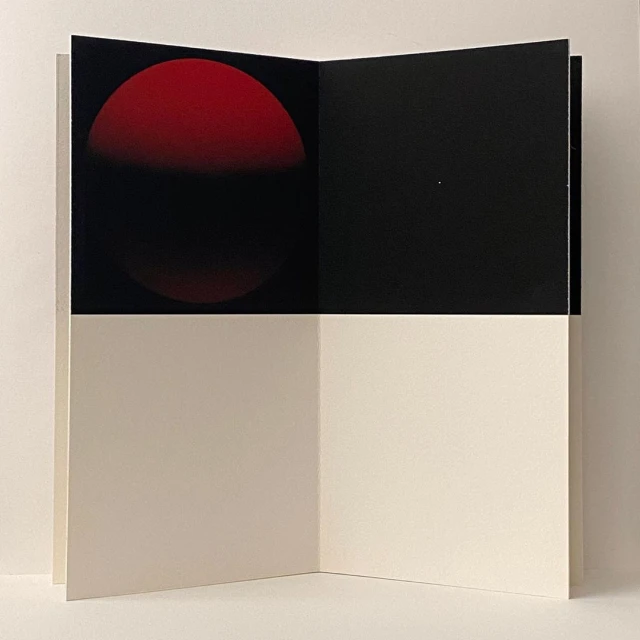 Open book with red circle and black background on upper half, with white space on the lower half of the interior pages.