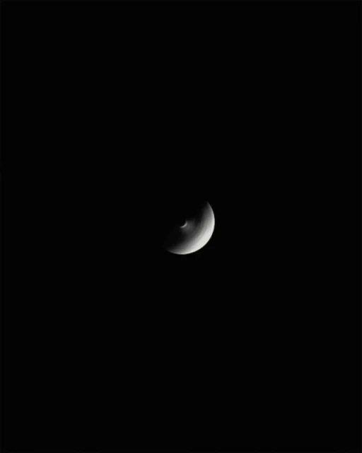 Crescent moon centered in an otherwise stark-black sky, showcasing its subtle curves and minimal illumination.